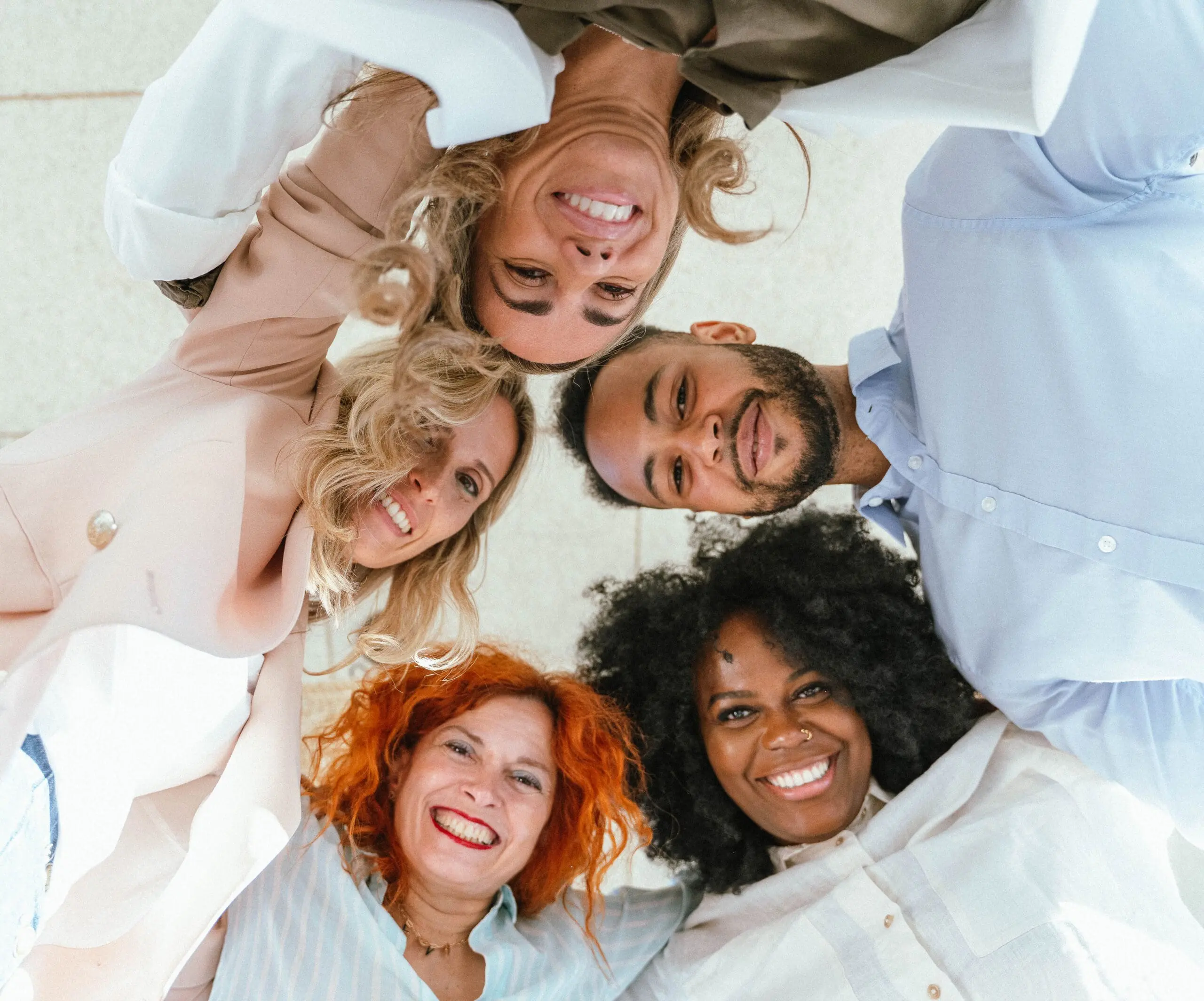 Diverse business colleagues embracing and smiling while standing in circle.